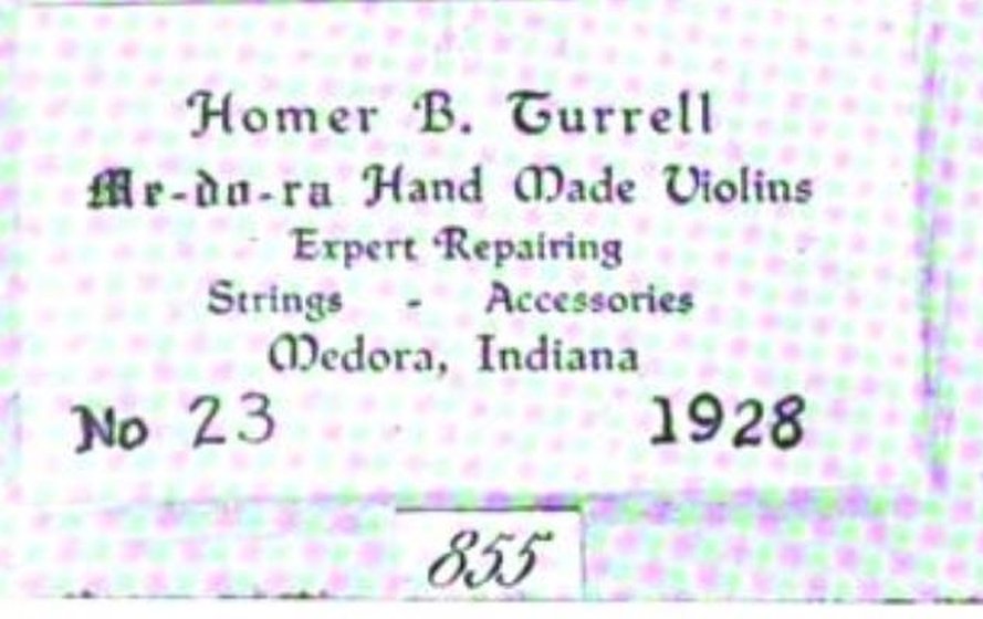 A printed violin label with no visible border rule, set in a blackletter face. The lines read Homer B. Turrell; then a hyphenated trade name, Me-do-ra, whose middle vowel is indistinct at this resolution, followed by Hand Made Violins; then Expert Repairing; then Strings - Accessories; then Medora, Indiana. A final line carries No at the left with 23 beside it and 1928 at the right, both numerals in a plain roman face unlike the rest of the label. Below the label the plate prints its facsimile number, 855, in a small ruled box. A coarse halftone dot screen from the 1930 printing lies over the whole image.